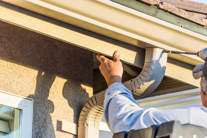 A team of workers installing seamless gutters on a commercial building in Springfield